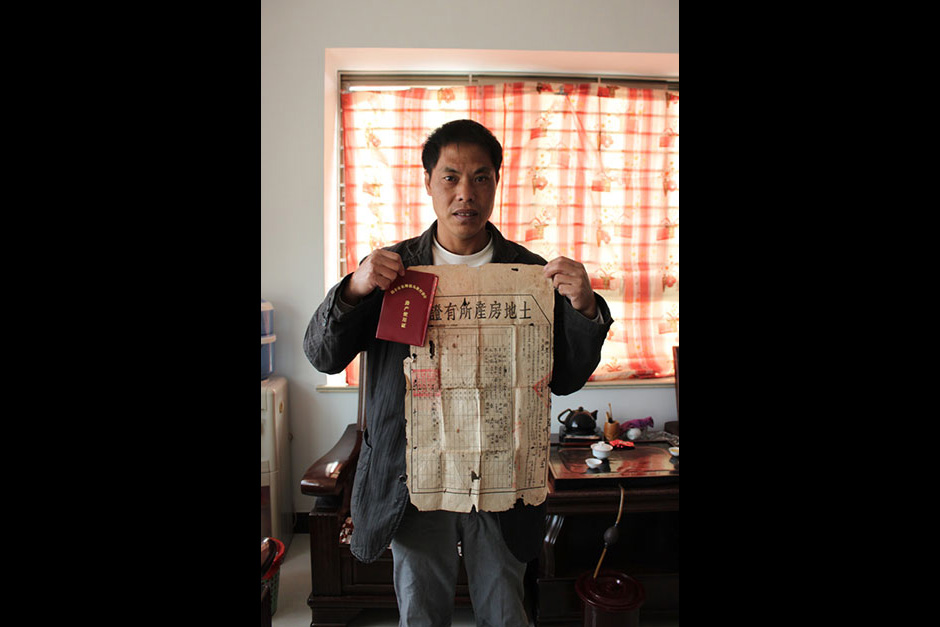 Villager Zhang Bingchai holds his land-lease contract and house property certificate in his home in Wukan.